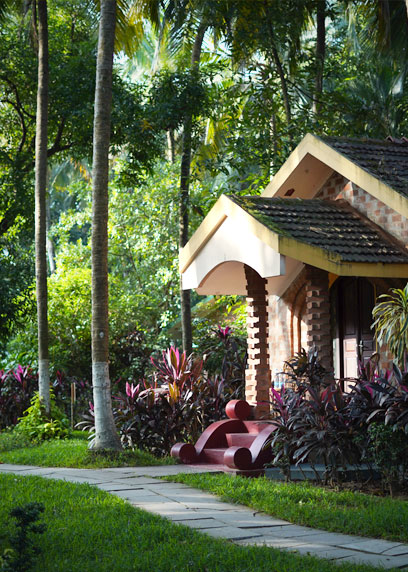 Entrance of the Royal Villa surrounded by lush green palm trees | Kairali-The Ayurvedic Healing Village